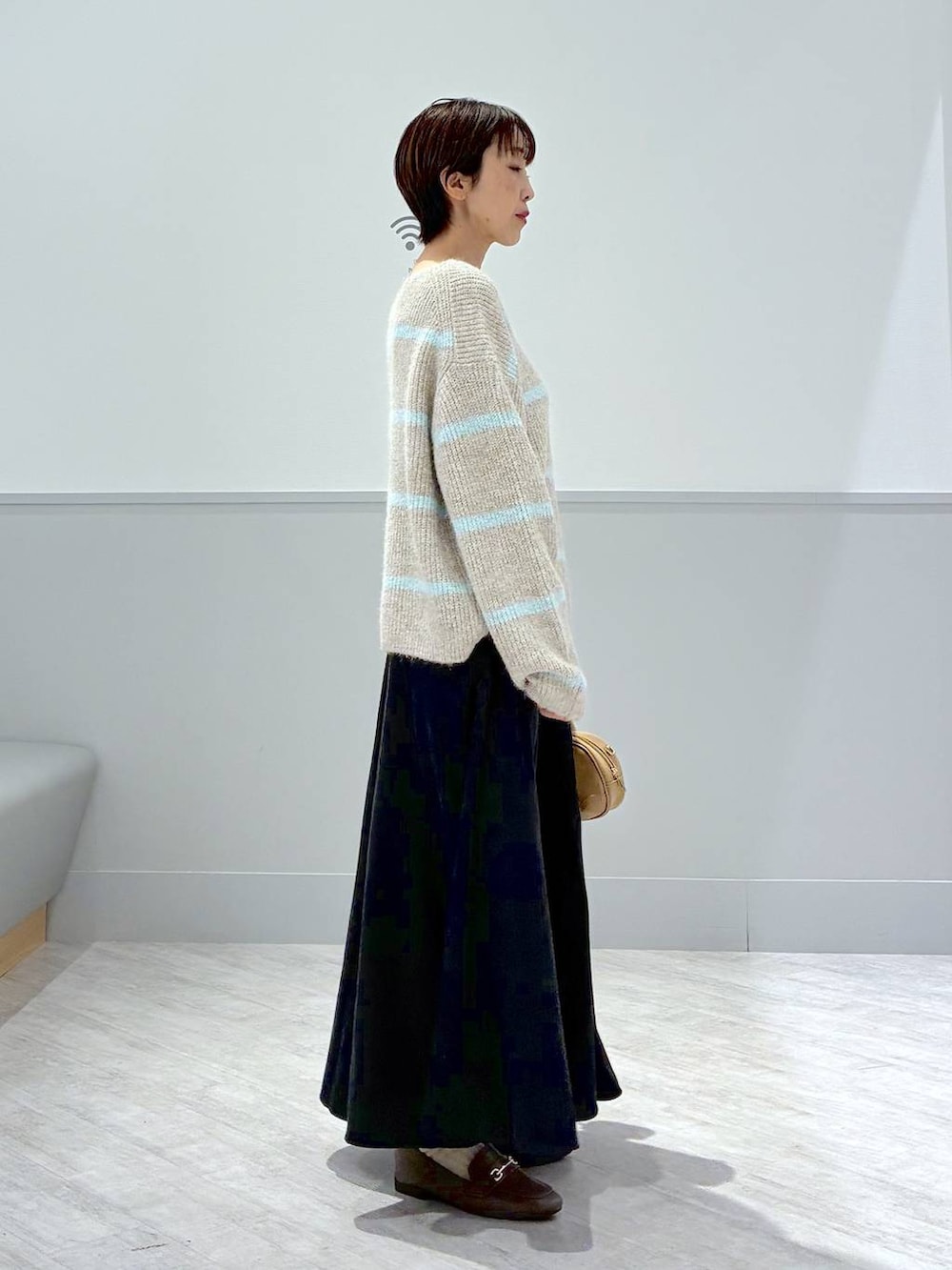 ベージュ系のローファー、グレー系のスカート、ブラウン系のハンドバッグを着用したレディースの秋コーディネートの5枚目の写真