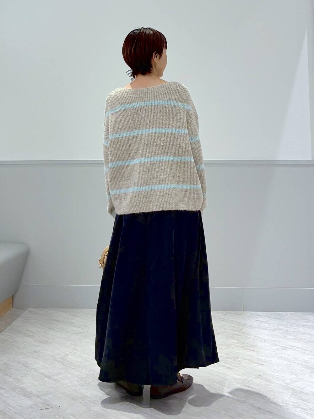 ベージュ系のローファー、グレー系のスカート、ブラウン系のハンドバッグを着用したレディースの秋コーディネートの4枚目の写真