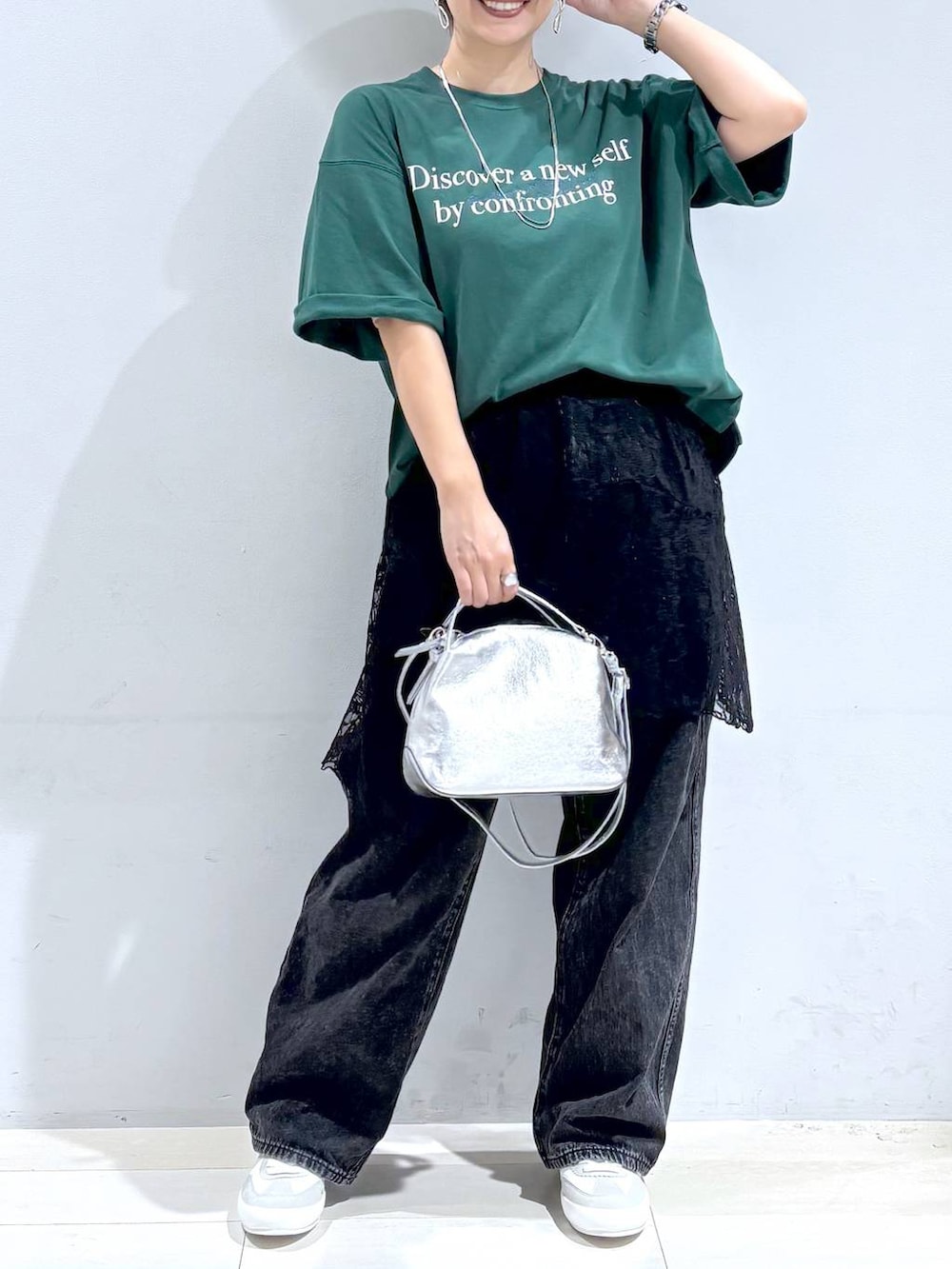 シルバー系のショルダーバッグ、ホワイト系のスニーカー、ブラック系のスカートを着用したレディースの秋コーディネートの2枚目の写真