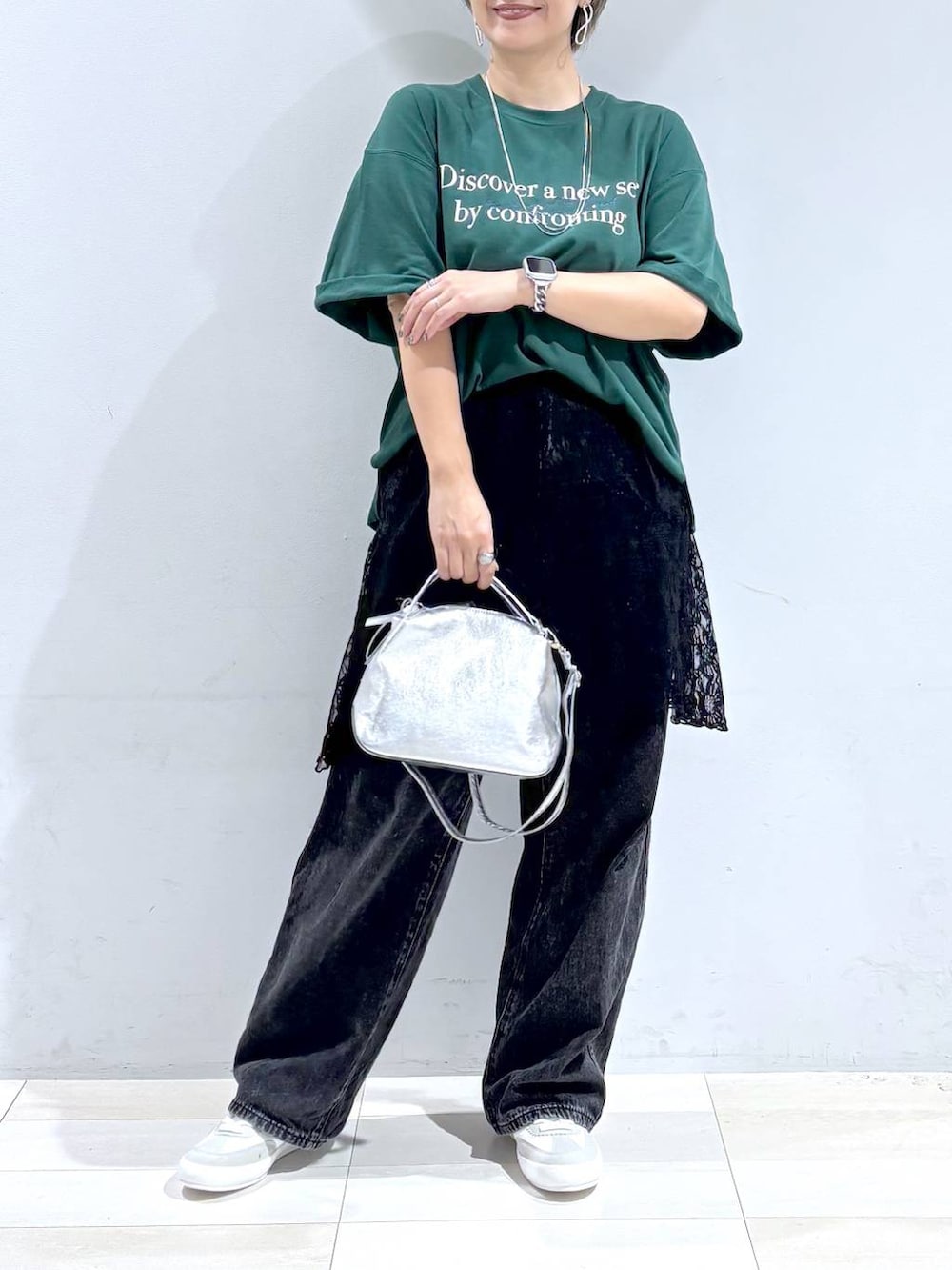 シルバー系のショルダーバッグ、ホワイト系のスニーカー、ブラック系のスカートを着用したレディースの秋コーディネートの3枚目の写真