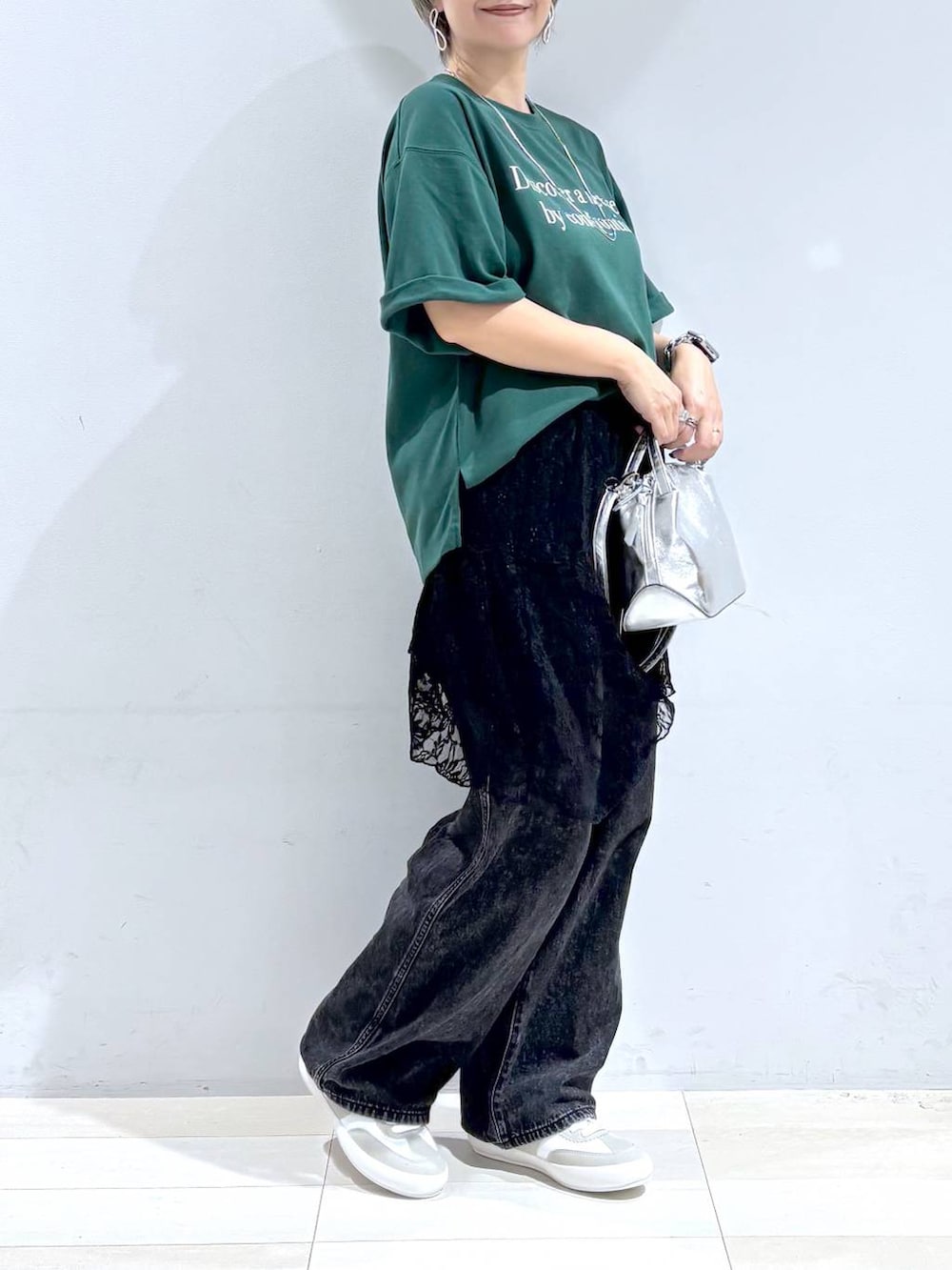 シルバー系のショルダーバッグ、ホワイト系のスニーカー、ブラック系のスカートを着用したレディースの秋コーディネートの5枚目の写真