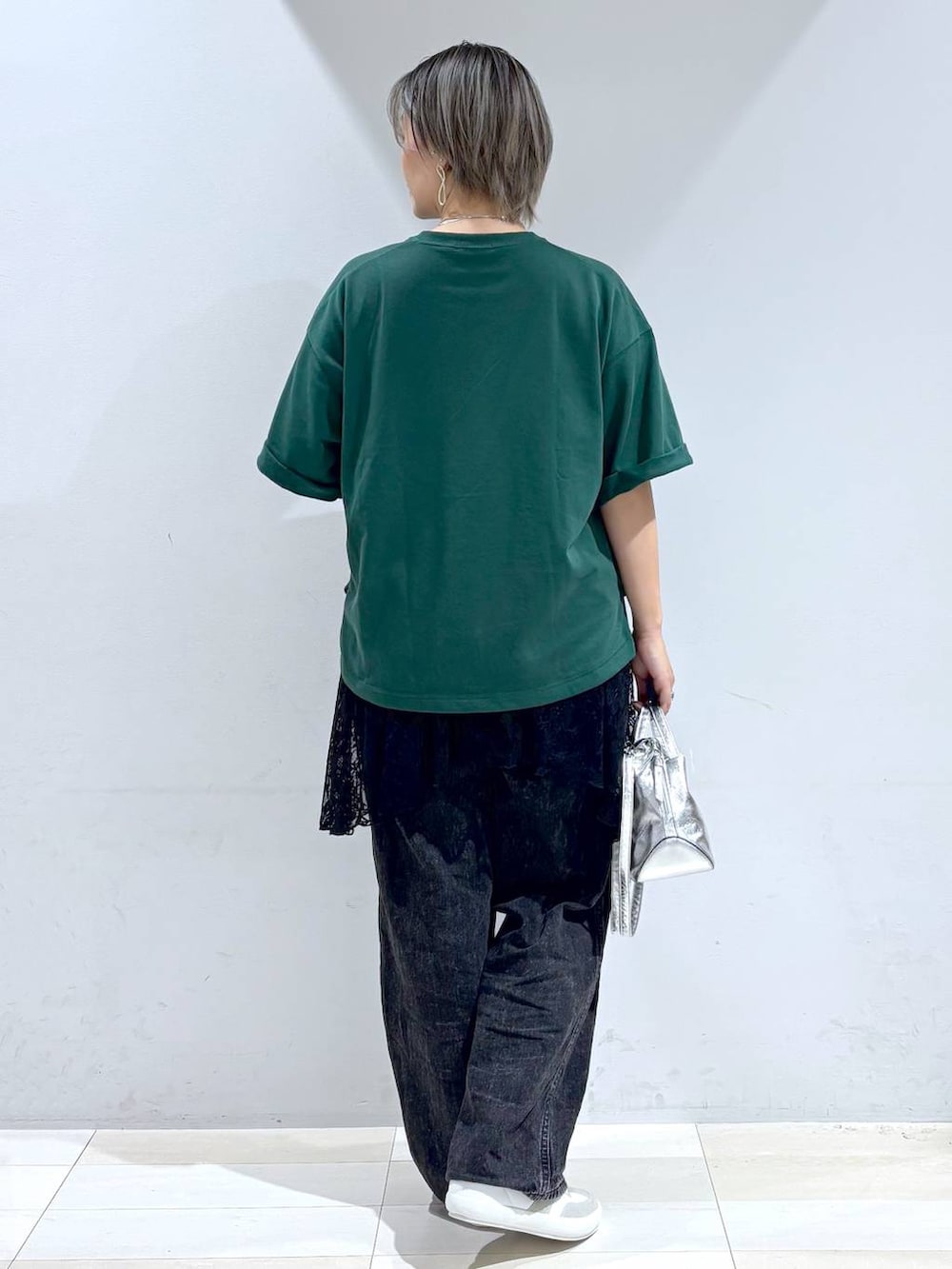 シルバー系のショルダーバッグ、ホワイト系のスニーカー、ブラック系のスカートを着用したレディースの秋コーディネートの6枚目の写真