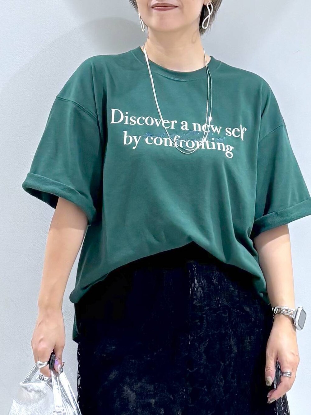 シルバー系のショルダーバッグ、ホワイト系のスニーカー、ブラック系のスカートを着用したレディースの秋コーディネートの4枚目の写真