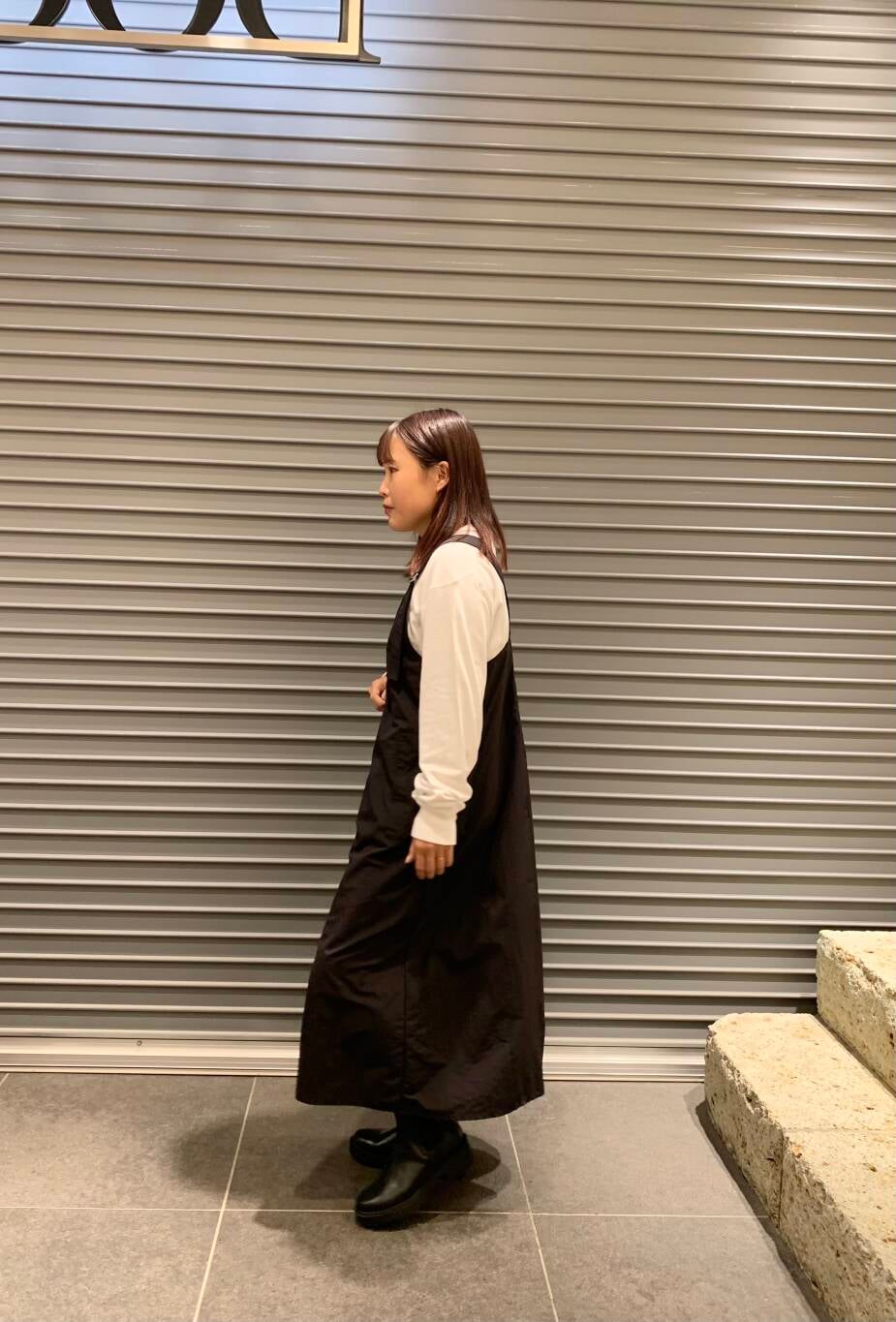 ブラック系のワンピース、ホワイト系のTシャツ/カットソー、ブラック系のブーツを着用したレディースの秋コーディネートの5枚目の写真