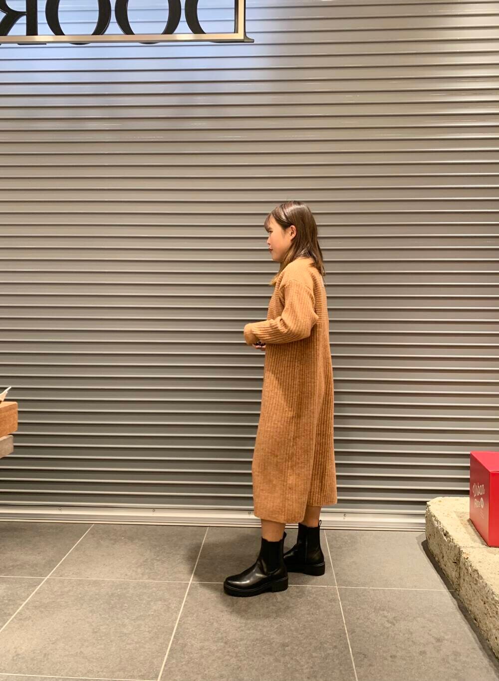 ホワイト系のダウンジャケット/コート、ブラック系のブーツ、オレンジ系のワンピースを着用したレディースの冬コーディネートの5枚目の写真