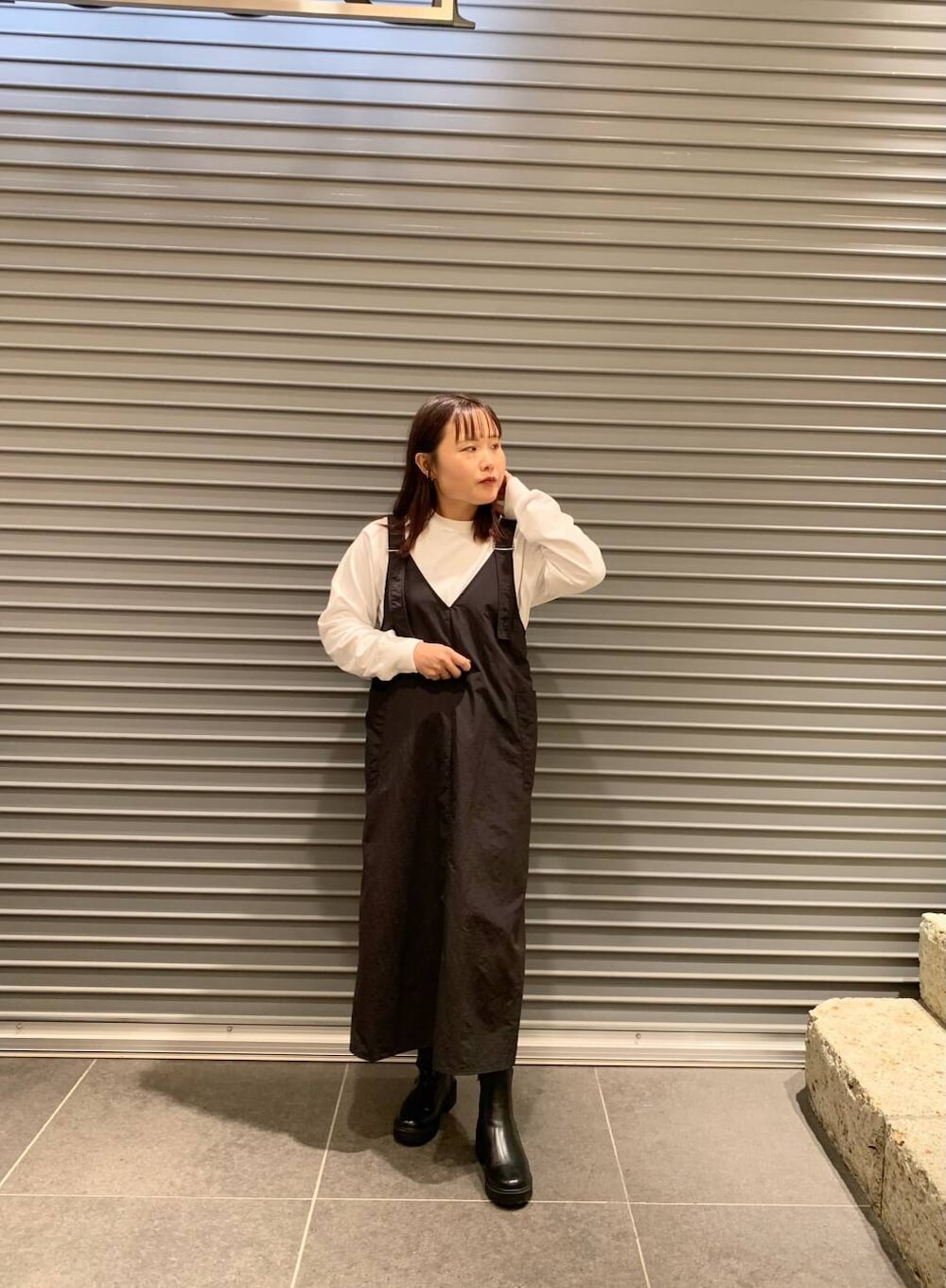 ブラック系のワンピース、ホワイト系のTシャツ/カットソー、ブラック系のブーツを着用したレディースの秋コーディネートの4枚目の写真