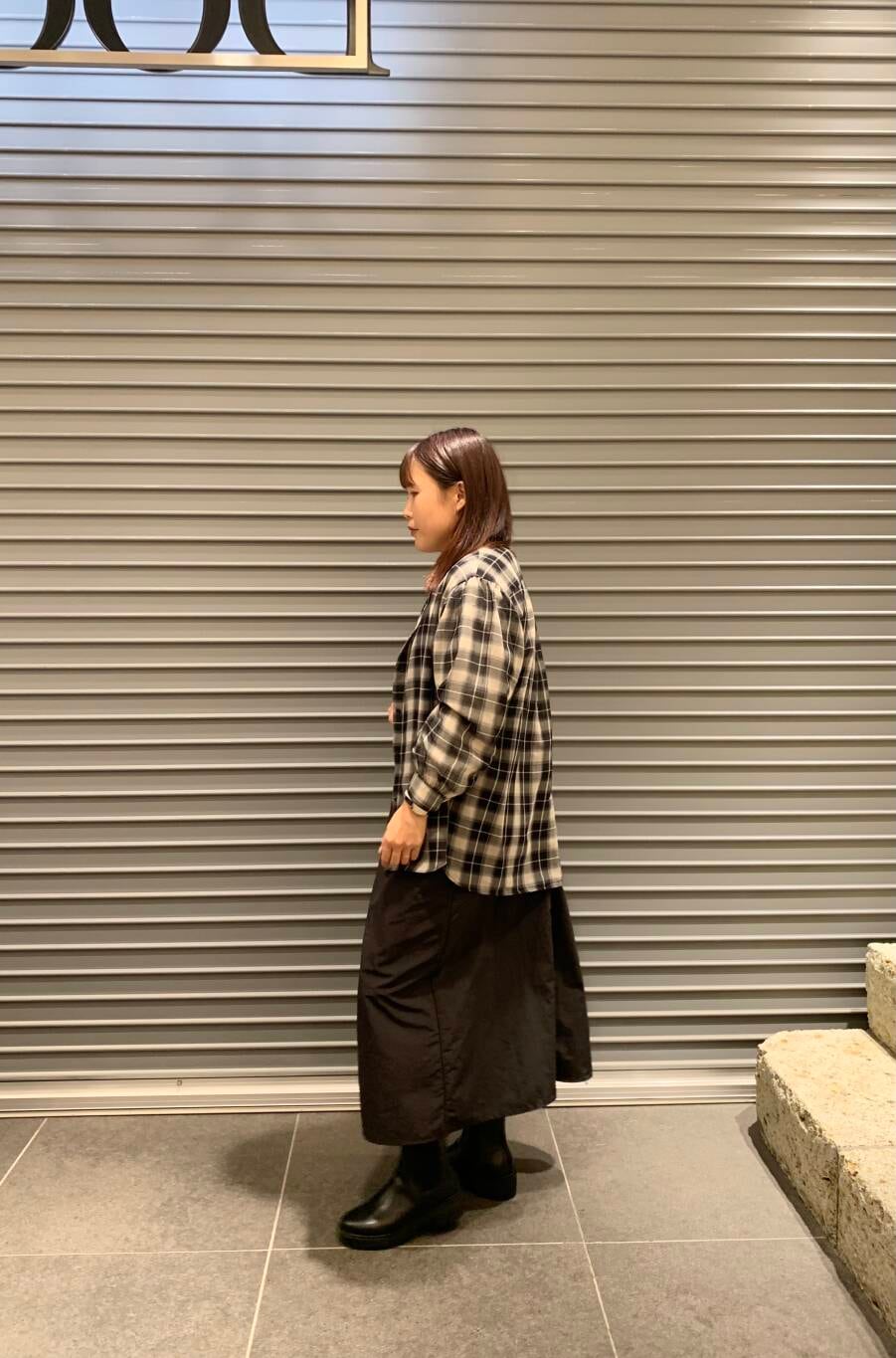 ブラック系のワンピース、ホワイト系のTシャツ/カットソー、ブラック系のブーツを着用したレディースの秋コーディネートの2枚目の写真