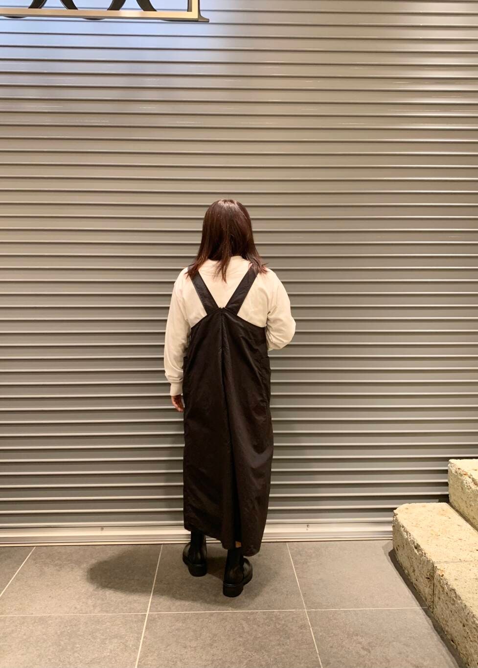 ブラック系のワンピース、ホワイト系のTシャツ/カットソー、ブラック系のブーツを着用したレディースの秋コーディネートの6枚目の写真