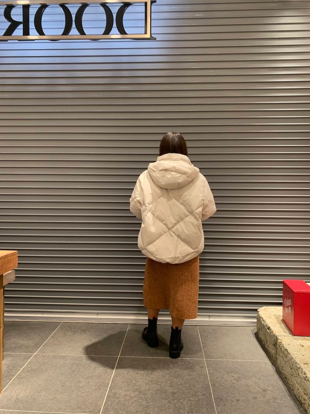 ホワイト系のダウンジャケット/コート、ブラック系のブーツ、オレンジ系のワンピースを着用したレディースの冬コーディネートの3枚目の写真