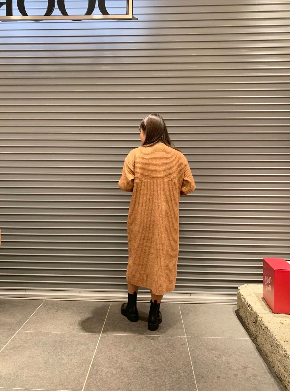 ホワイト系のダウンジャケット/コート、ブラック系のブーツ、オレンジ系のワンピースを着用したレディースの冬コーディネートの6枚目の写真