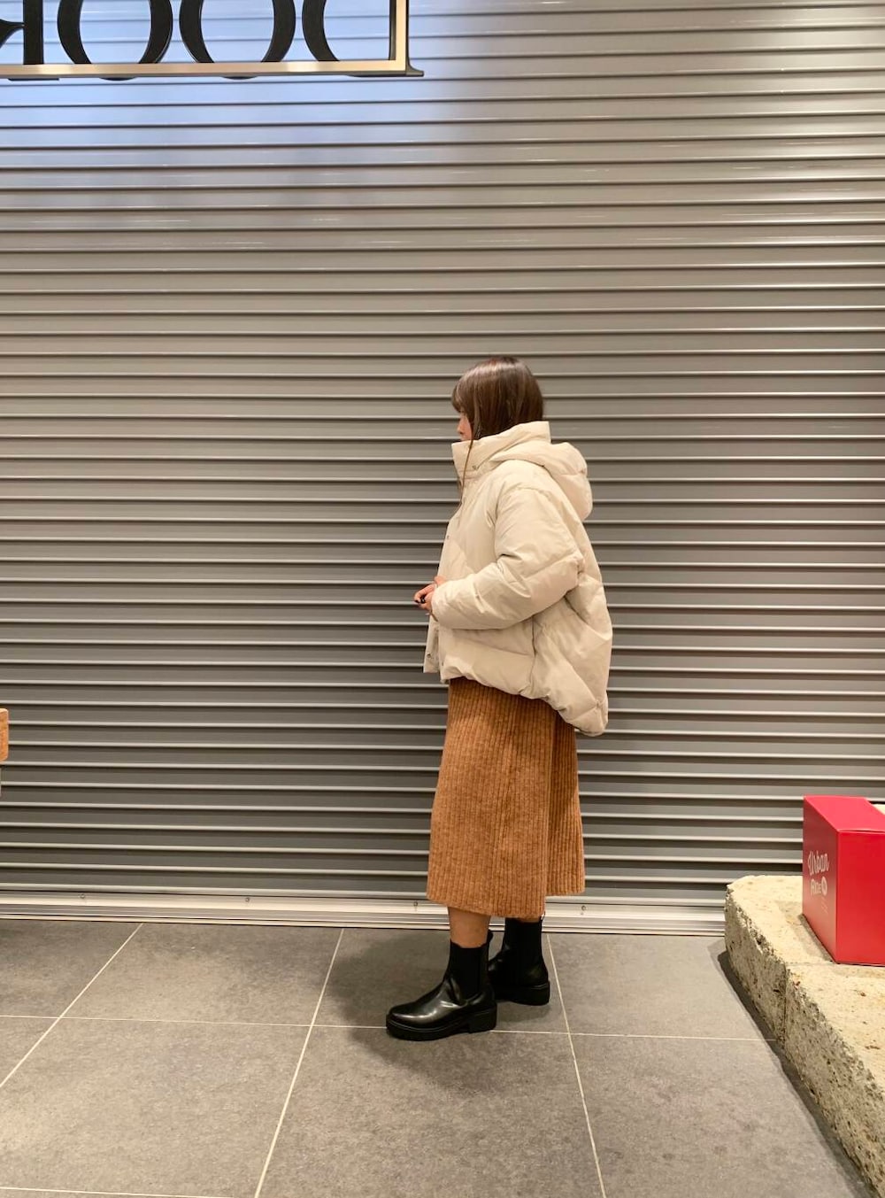 ホワイト系のダウンジャケット/コート、ブラック系のブーツ、オレンジ系のワンピースを着用したレディースの冬コーディネートの2枚目の写真