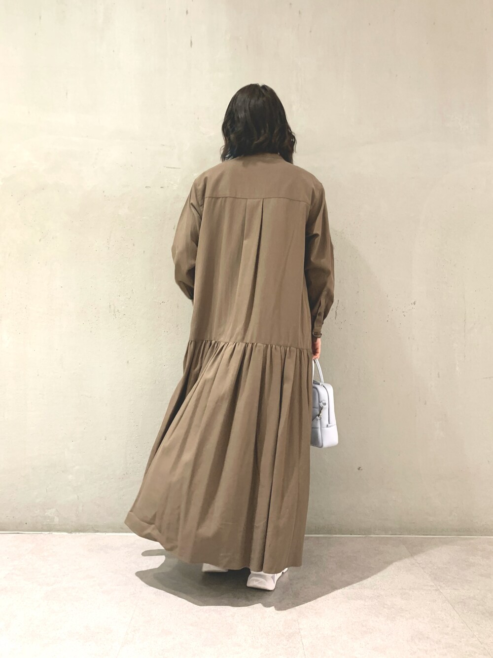 グリーン系のワンピース、ブルー系のハンドバッグ、ゴールド系のネックレスを着用したレディースの冬コーディネートの2枚目の写真