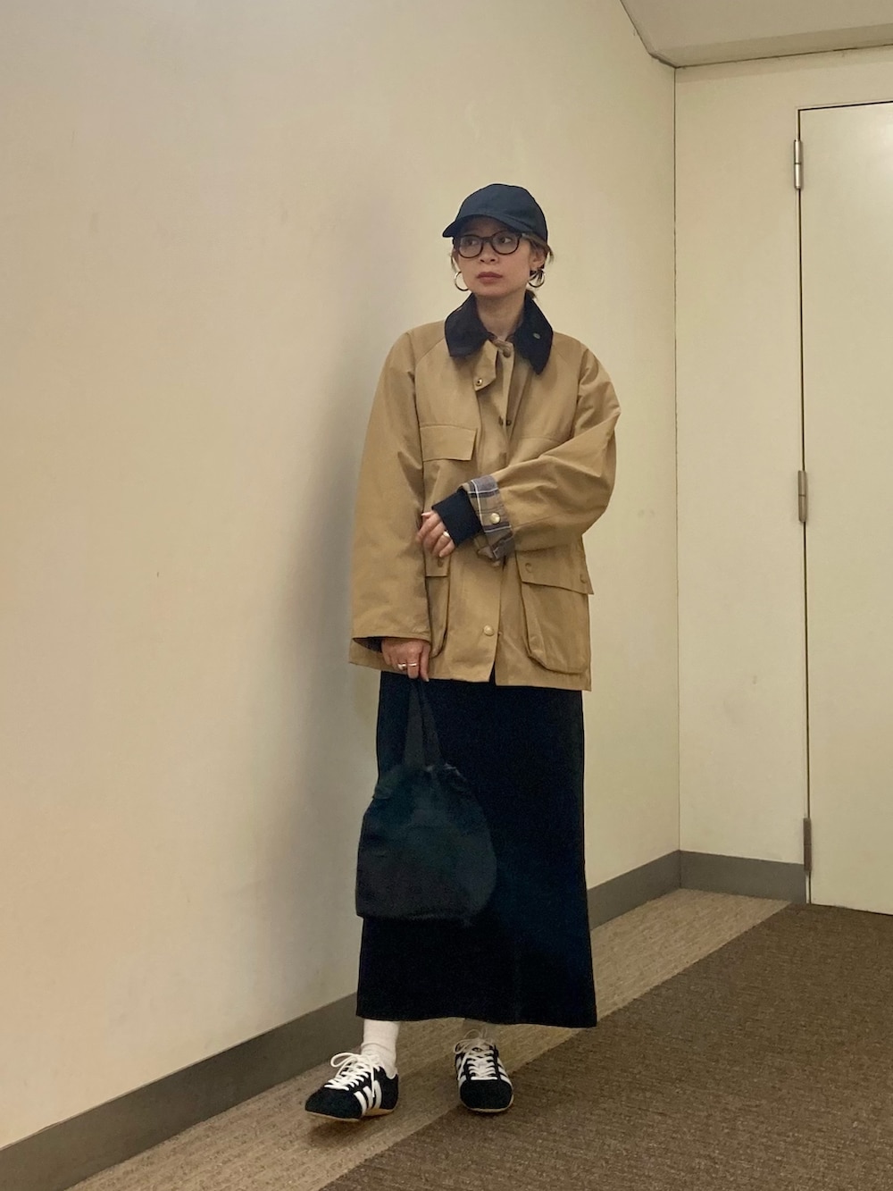 ベージュ系のその他アウター、ブラック系のスカート、ブラック系のショルダーバッグを着用したレディースの秋コーディネートの4枚目の写真