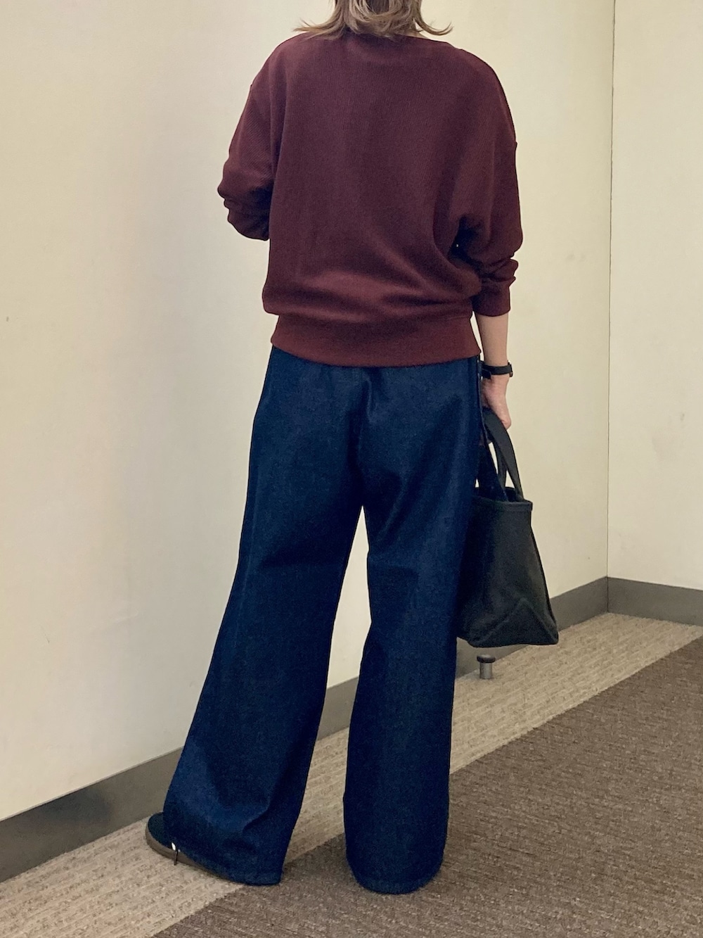 レッド系のカーディガン/ボレロ、ブルー系のデニムパンツ、グレー系のトートバッグを着用したレディースの秋コーディネートの2枚目の写真