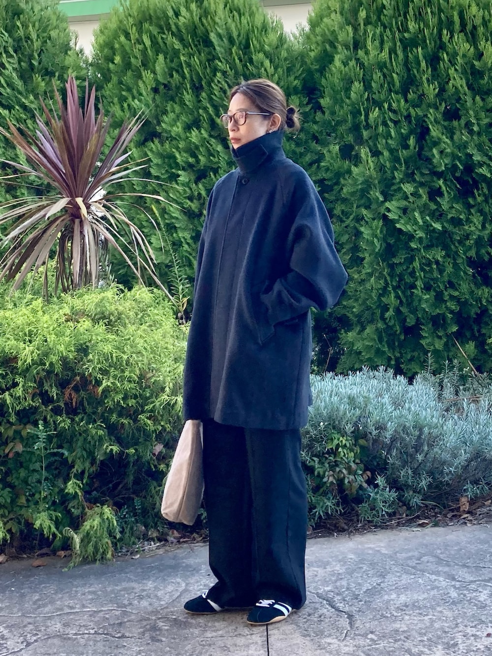 グレー系のステンカラーコート、ブラック系のその他パンツ、ブラック系のスニーカーを着用したレディースの秋コーディネートの2枚目の写真