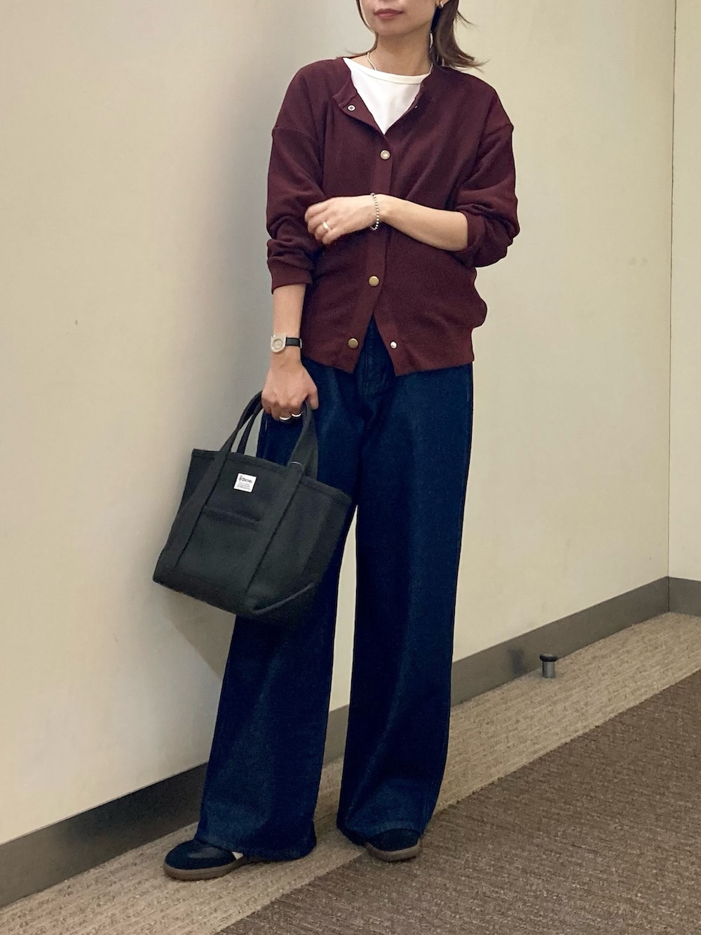 レッド系のカーディガン/ボレロ、ブルー系のデニムパンツ、グレー系のトートバッグを着用したレディースの秋コーディネートの3枚目の写真