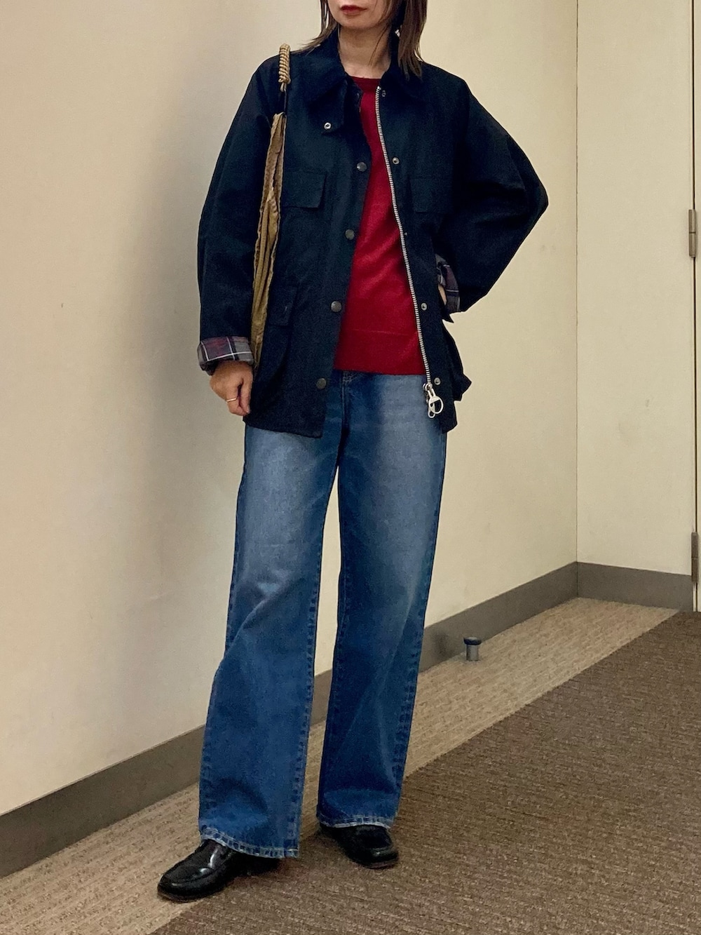ブラック系のその他アウター、ブルー系のデニムパンツ、レッド系のニット/セーターを着用したレディースの秋コーディネートの2枚目の写真