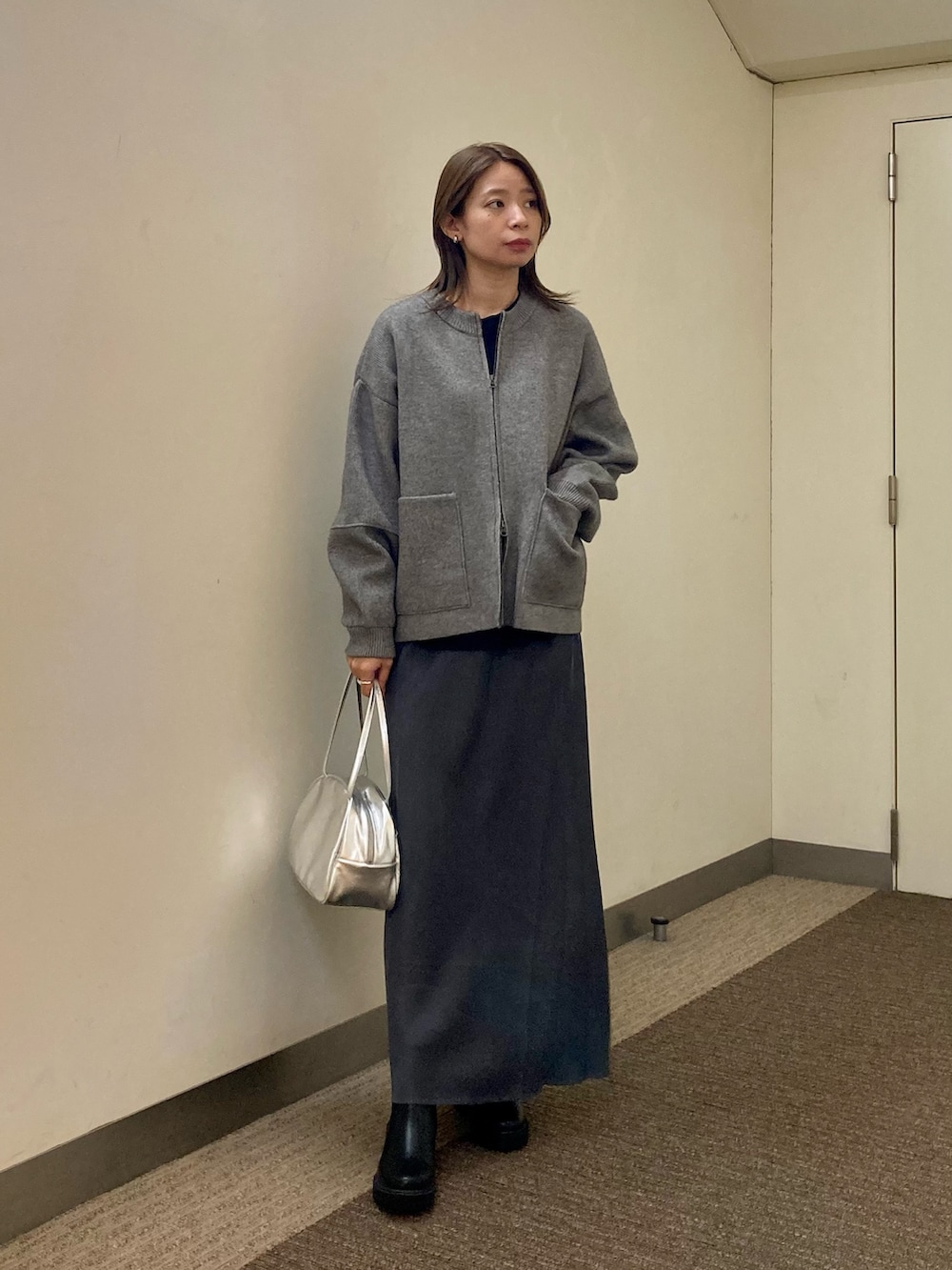 グレー系のニット/セーター、ブラック系のTシャツ/カットソー、グレー系のスカートを着用したレディースの秋コーディネートの5枚目の写真