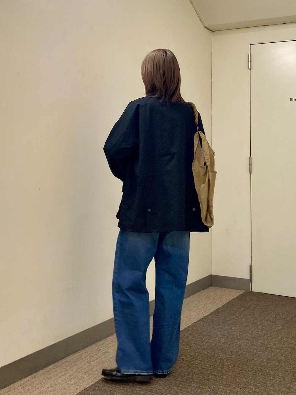 ブラック系のその他アウター、ブルー系のデニムパンツ、レッド系のニット/セーターを着用したレディースの秋コーディネートの4枚目の写真