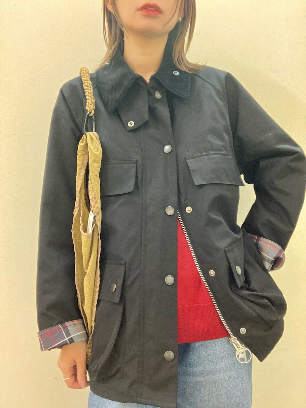 ブラック系のその他アウター、ブルー系のデニムパンツ、レッド系のニット/セーターを着用したレディースの秋コーディネートの5枚目の写真