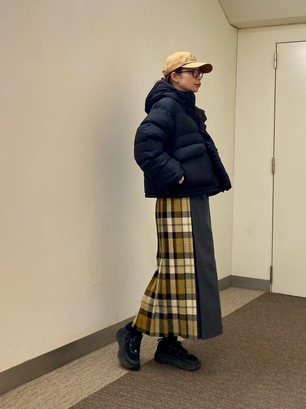 ベージュ系のスカート、ブラック系のダウンジャケット/コート、ベージュ系のキャップを着用したレディースの秋コーディネートの3枚目の写真