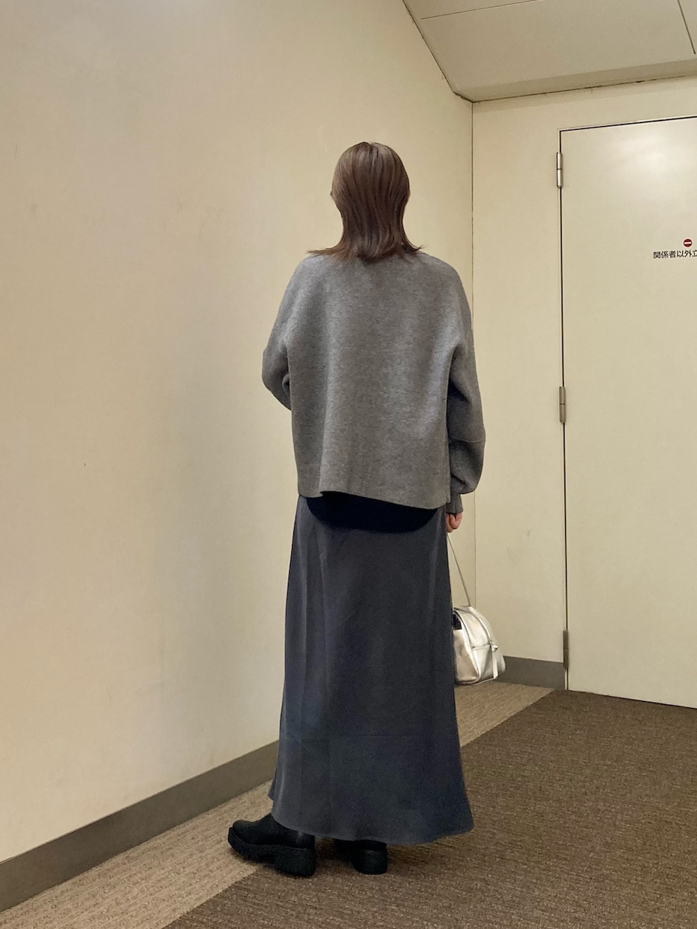 グレー系のニット/セーター、ブラック系のTシャツ/カットソー、グレー系のスカートを着用したレディースの秋コーディネートの4枚目の写真