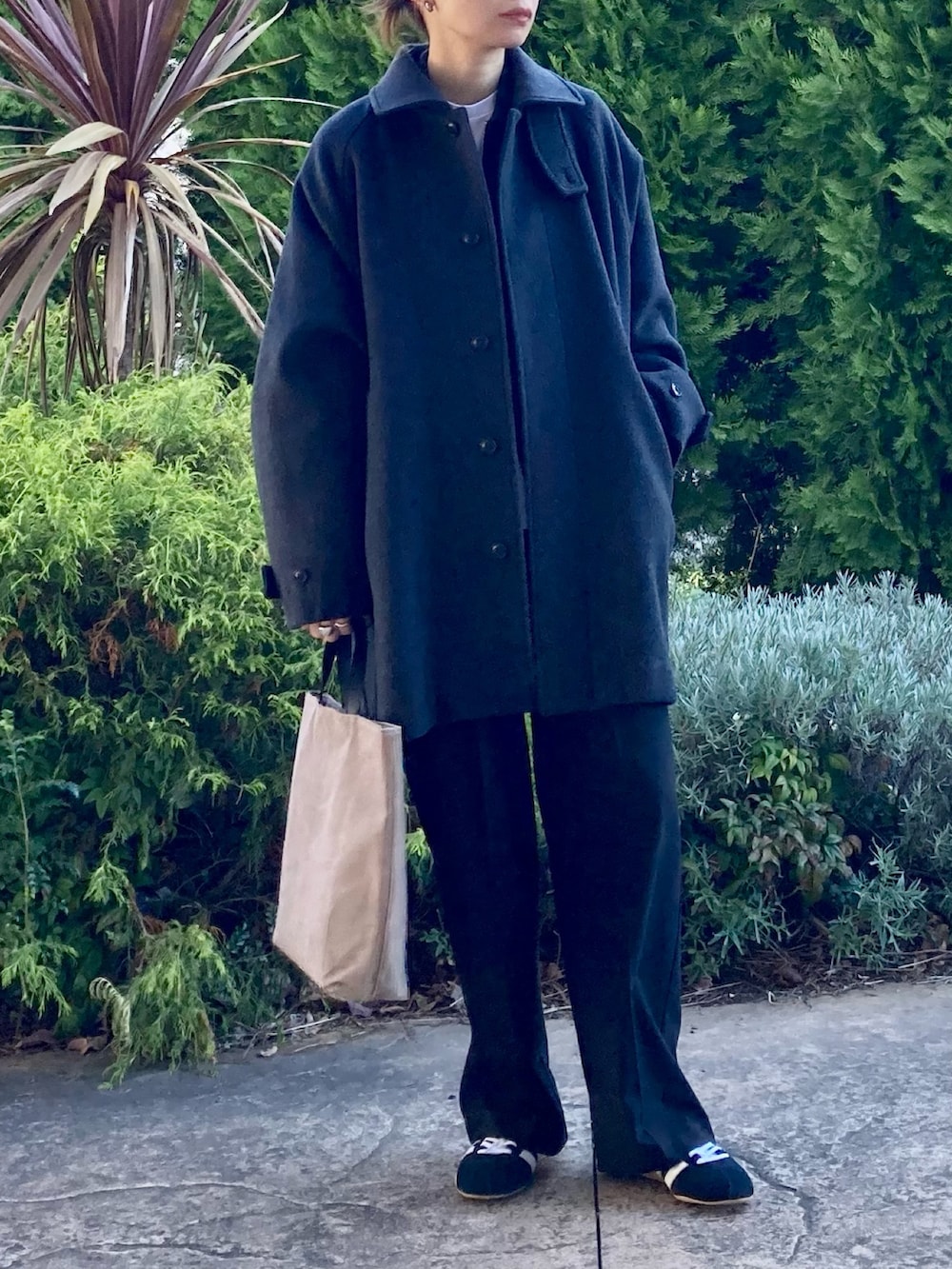 グレー系のステンカラーコート、ブラック系のその他パンツ、ブラック系のスニーカーを着用したレディースの秋コーディネートの4枚目の写真