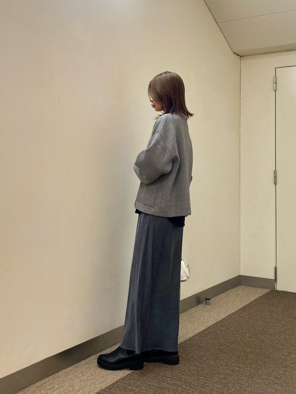グレー系のニット/セーター、ブラック系のTシャツ/カットソー、グレー系のスカートを着用したレディースの秋コーディネートの3枚目の写真