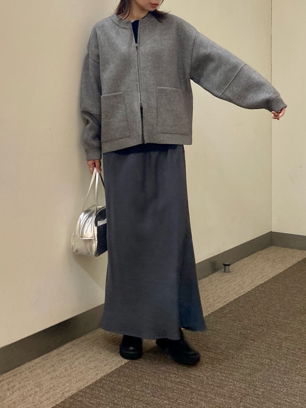 グレー系のニット/セーター、ブラック系のTシャツ/カットソー、グレー系のスカートを着用したレディースの秋コーディネートの2枚目の写真