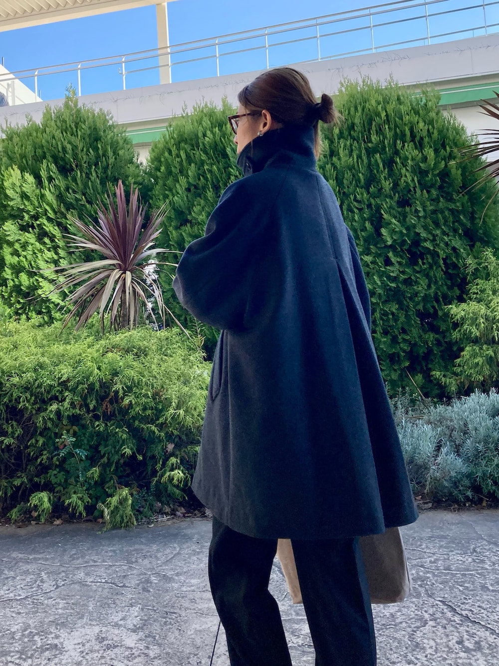 グレー系のステンカラーコート、ブラック系のその他パンツ、ブラック系のスニーカーを着用したレディースの秋コーディネートの3枚目の写真