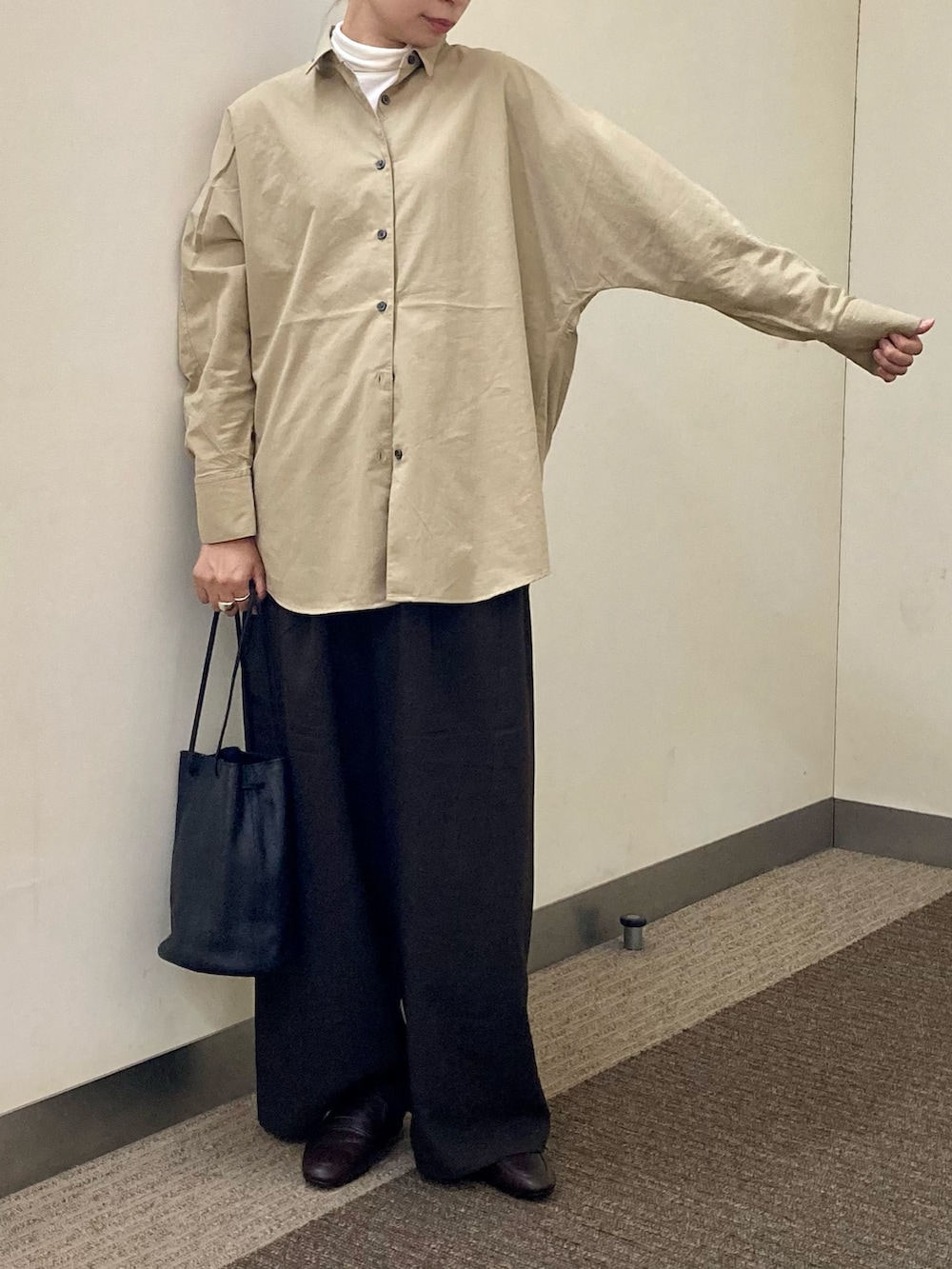 ブラウン系のパンプス、ブラック系のショルダーバッグ、ホワイト系のTシャツ/カットソーを着用したレディースの秋コーディネートの2枚目の写真