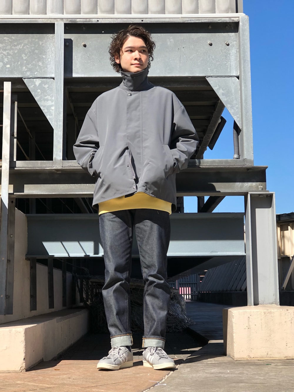 グレー系のその他アウター、イエロー系のスウェット、ブルー系のデニムパンツを着用したメンズの冬コーディネートの2枚目の写真