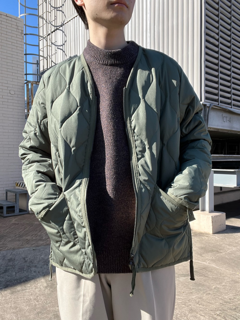 ブラウン系のニット/セーター、グリーン系のミリタリージャケット、ベージュ系のその他パンツを着用したメンズの秋コーディネートの3枚目の写真