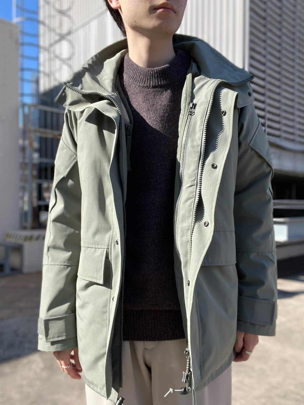 ブラウン系のニット/セーター、グリーン系のミリタリージャケット、ベージュ系のその他パンツを着用したメンズの秋コーディネートの2枚目の写真