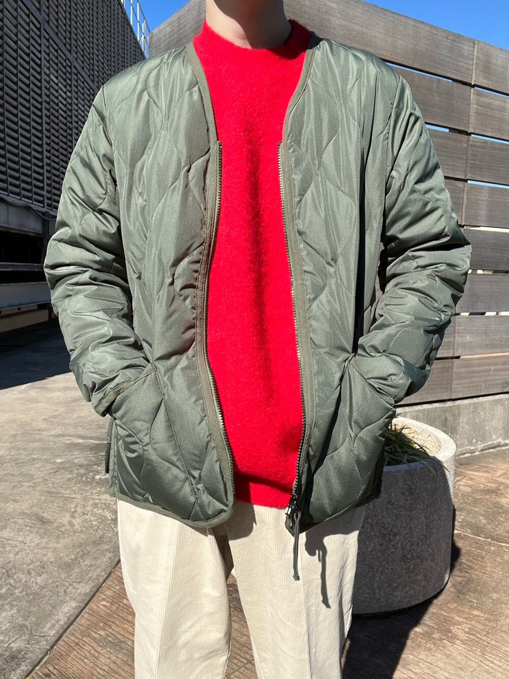 レッド系のニット/セーター、グリーン系のモッズコート、ホワイト系のその他パンツを着用したメンズの秋コーディネートの3枚目の写真