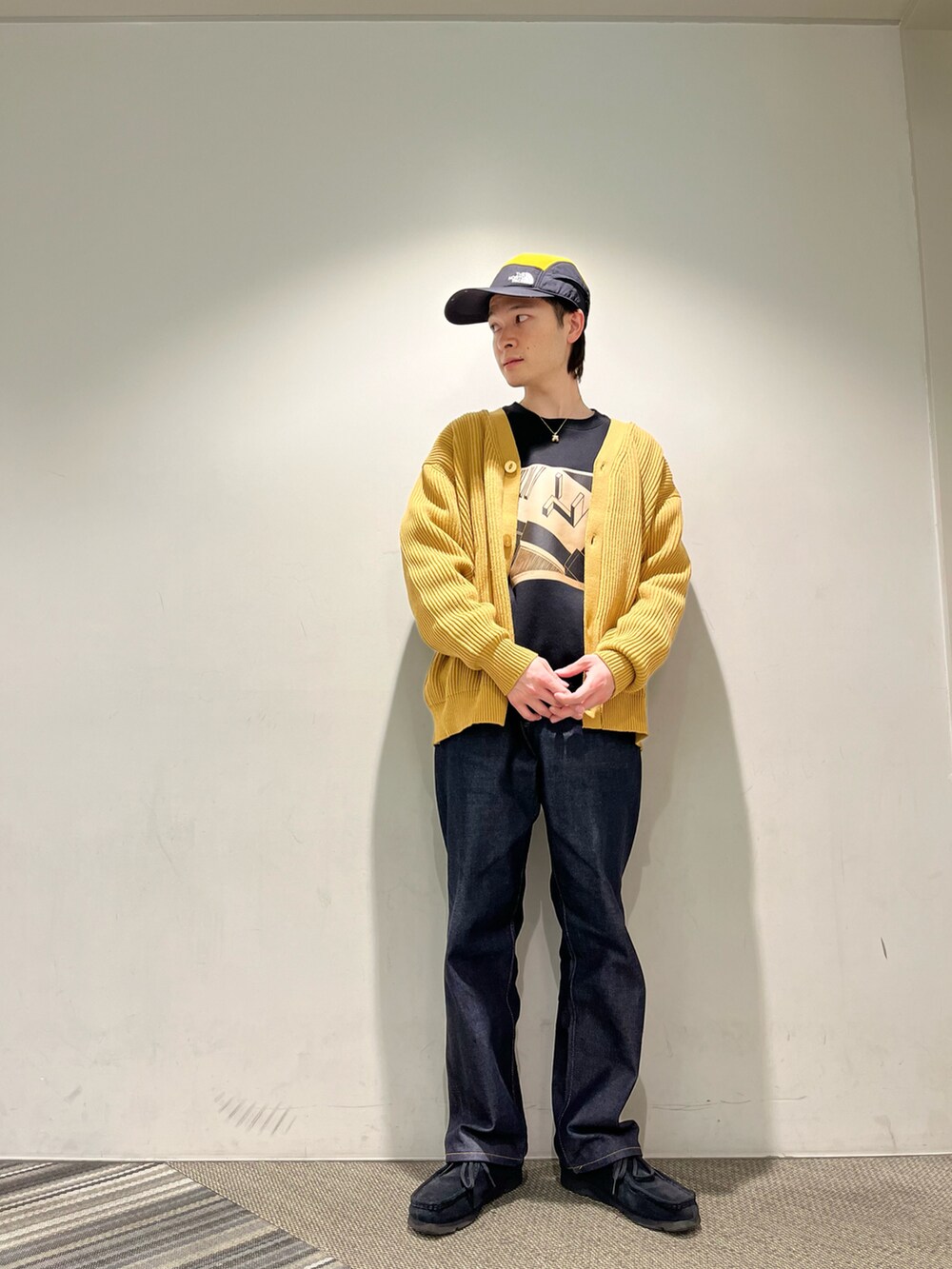 ブラック系のスウェット、ゴールド系のカーディガン/ボレロ、ブルー系のデニムパンツを着用したメンズの冬コーディネートの2枚目の写真