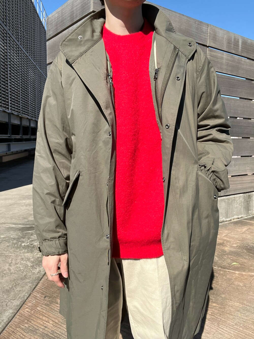 レッド系のニット/セーター、グリーン系のモッズコート、ホワイト系のその他パンツを着用したメンズの秋コーディネートの2枚目の写真