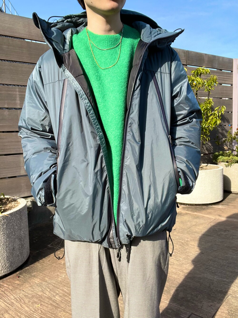 ブルー系のダウンジャケット/コート、グリーン系のニット/セーター、その他のその他パンツを着用したメンズの秋コーディネートの2枚目の写真