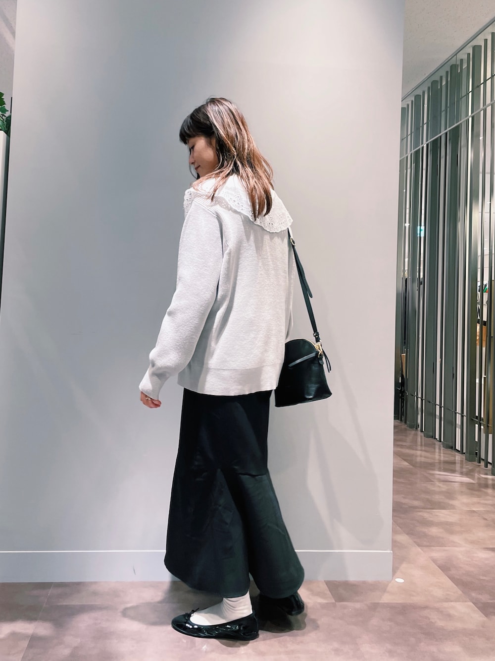 ブラック系のスカート、ベージュ系のニット/セーター、ブラック系のショルダーバッグを着用したレディースの春コーディネートの2枚目の写真