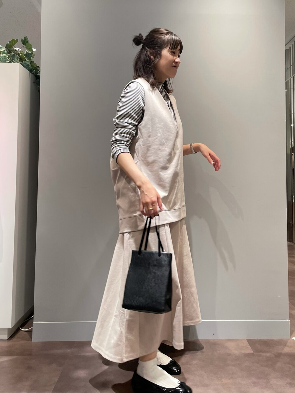 ブラック系のバレエシューズ、ブラック系のトートバッグ、ベージュ系のスカートを着用したレディースの秋コーディネートの2枚目の写真