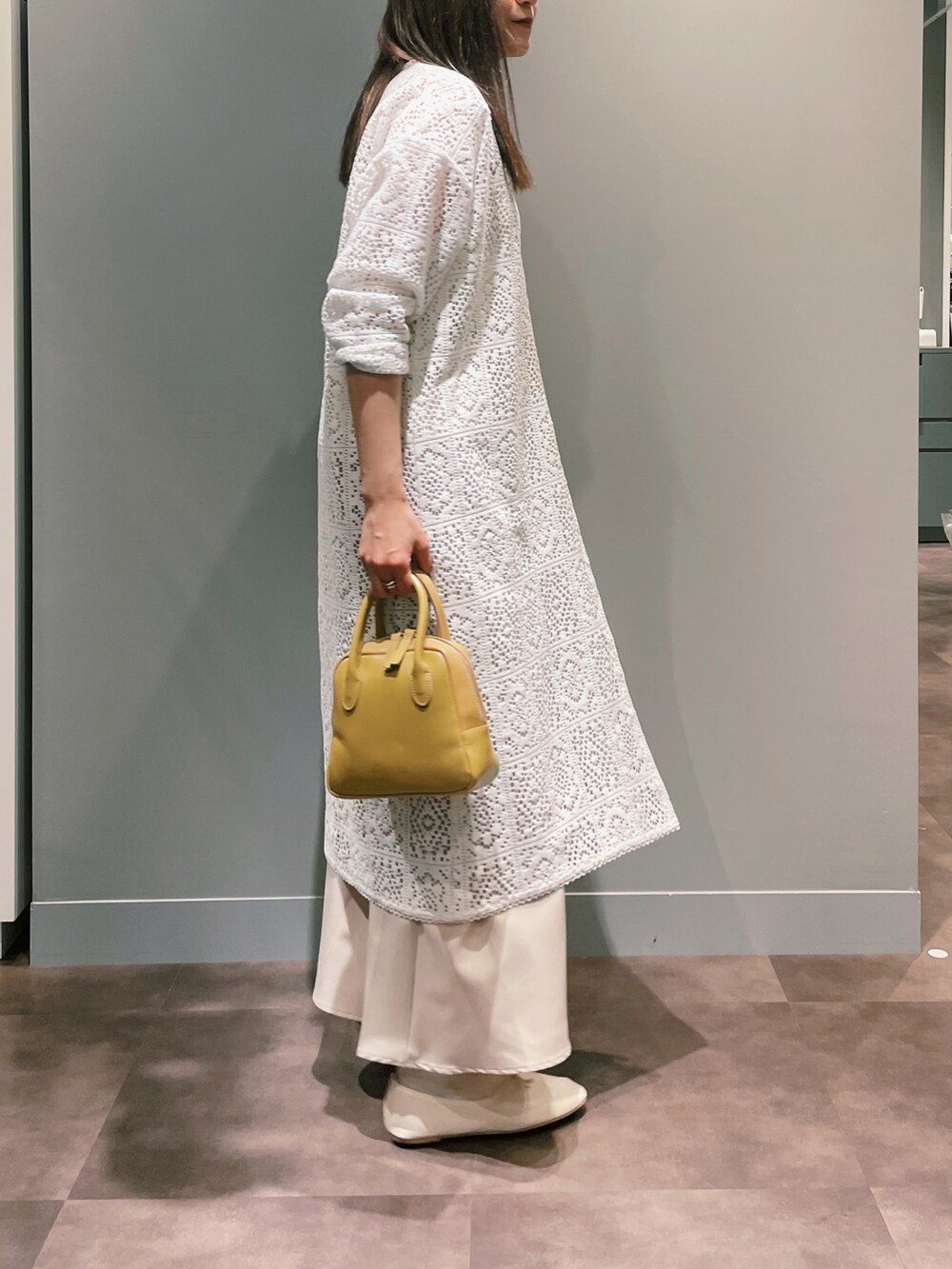 イエロー系のハンドバッグ、ホワイト系のワンピース、ベージュ系のスカートを着用したレディースの冬コーディネートの3枚目の写真