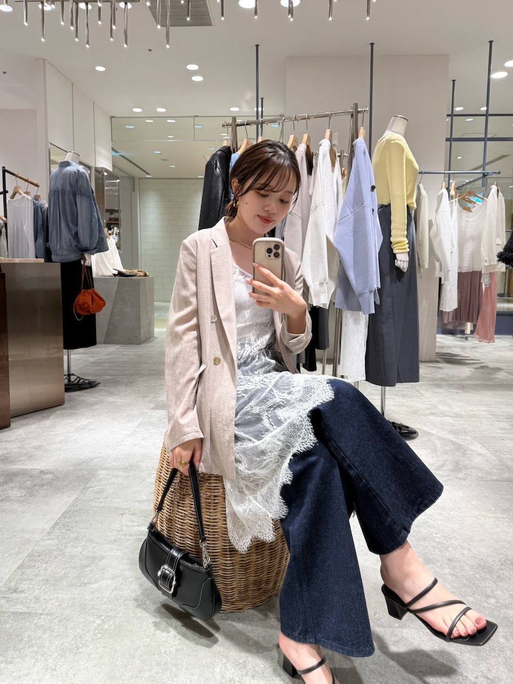 ベージュ系のテーラードジャケット、ブルー系のデニムパンツ、ブラック系のハンドバッグを着用したレディースの春コーディネートの2枚目の写真