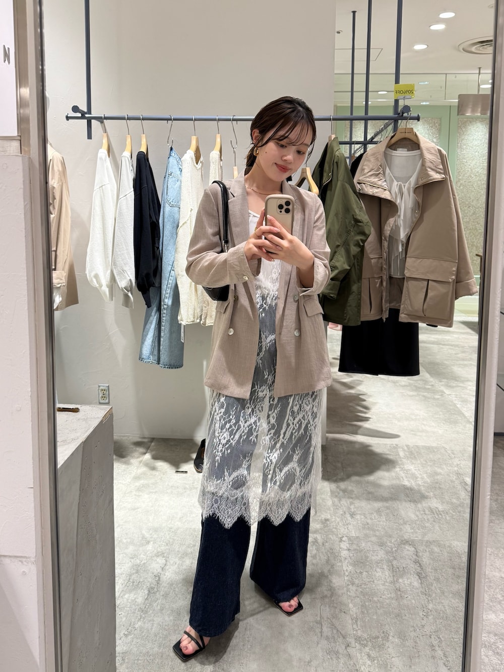 ベージュ系のテーラードジャケット、ブルー系のデニムパンツ、ブラック系のハンドバッグを着用したレディースの春コーディネートの3枚目の写真