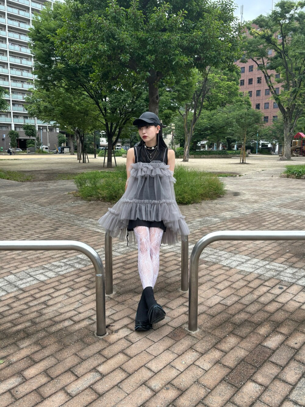 グレー系のキャミソール、ブラック系のスニーカー、ブラック系のキャップを着用したレディースの夏コーディネートの2枚目の写真