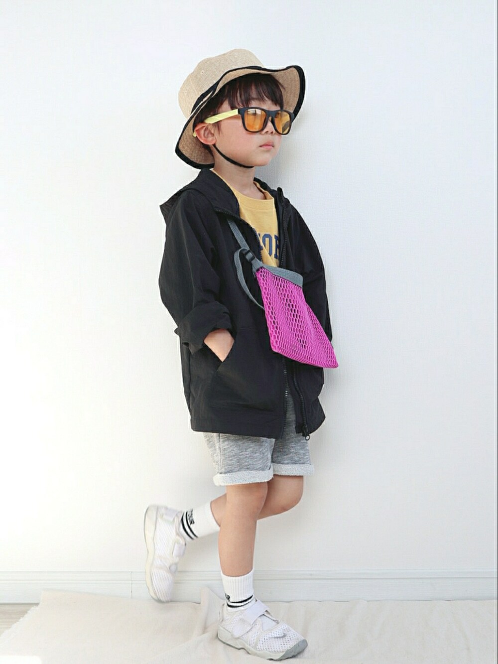 ブラック系のナイロンジャケット、イエロー系のTシャツ/カットソー、パープル系のショルダーバッグを着用したキッズの春コーディネートの2枚目の写真