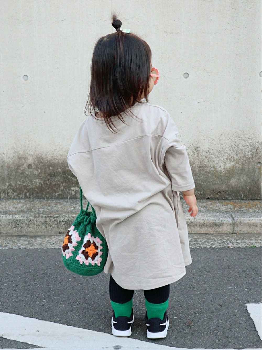 ベージュ系のワンピース、グリーン系のバッグ、ブラック系のスニーカーを着用したキッズの春コーディネートの3枚目の写真