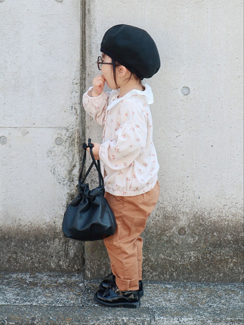 ブラック系のトートバッグ、ベージュ系のカーディガン/ボレロ、ベージュ系のチノパンツを着用したキッズの春コーディネートの2枚目の写真