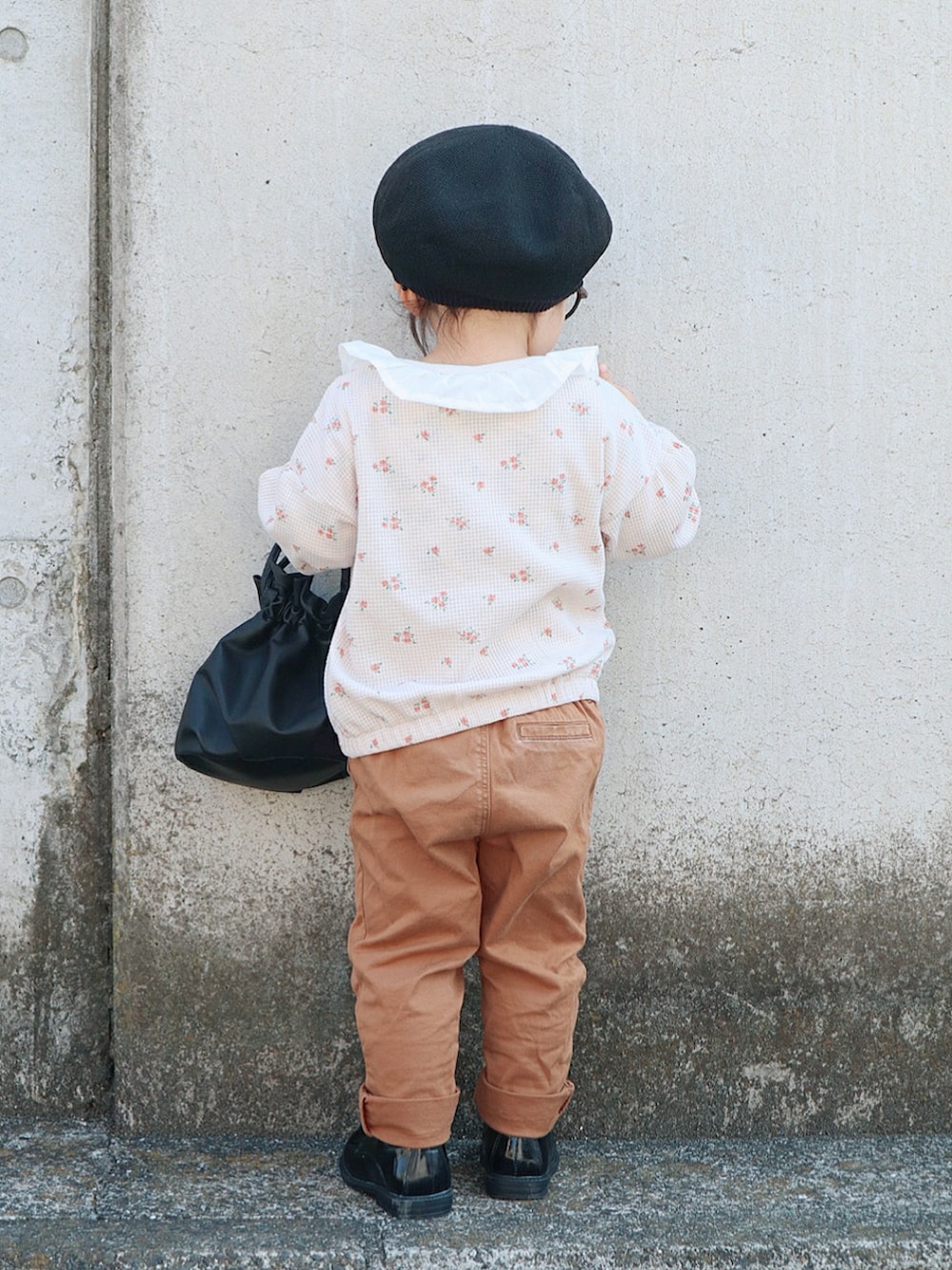 ブラック系のトートバッグ、ベージュ系のカーディガン/ボレロ、ベージュ系のチノパンツを着用したキッズの春コーディネートの3枚目の写真
