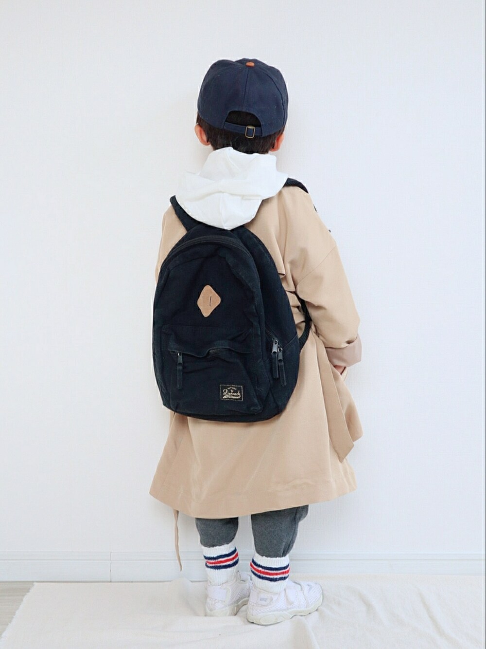 ベージュ系のトレンチコート、ホワイト系のパーカー、グレー系のスウェットパンツを着用したキッズの春コーディネートの3枚目の写真