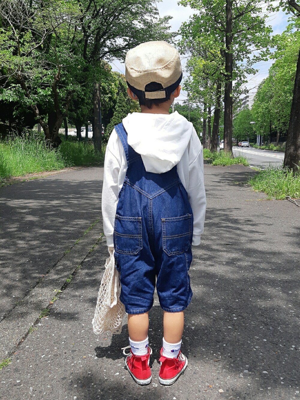 ホワイト系のパーカー、ブルー系のサロペット/オーバーオール、レッド系のスニーカーを着用したキッズの春コーディネートの2枚目の写真